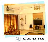 Lampshade, wall hanging, lantern, chandelier and use of wooden furniture coupled with a sleek television and music system give a fusion look